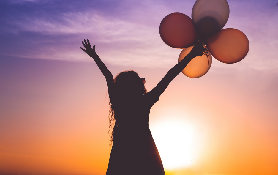 Excited lady with balloons watching sunset